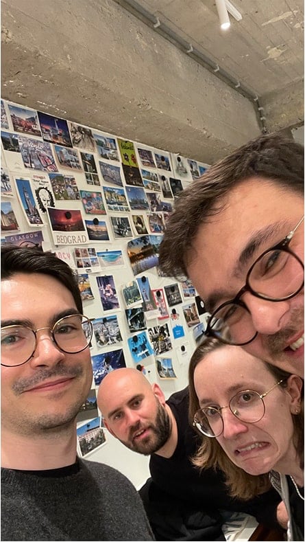 Adrien, Toon, Florence et Jonathan devant un mur de cartes postales